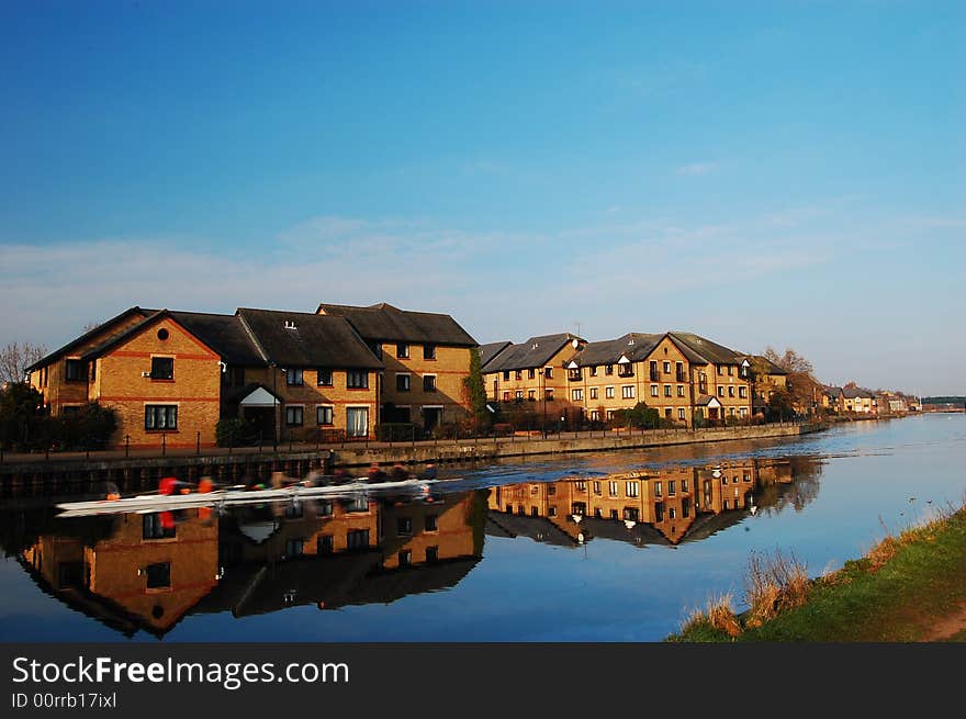 Boat of eight rowing on a river with reflection. Boat of eight rowing on a river with reflection