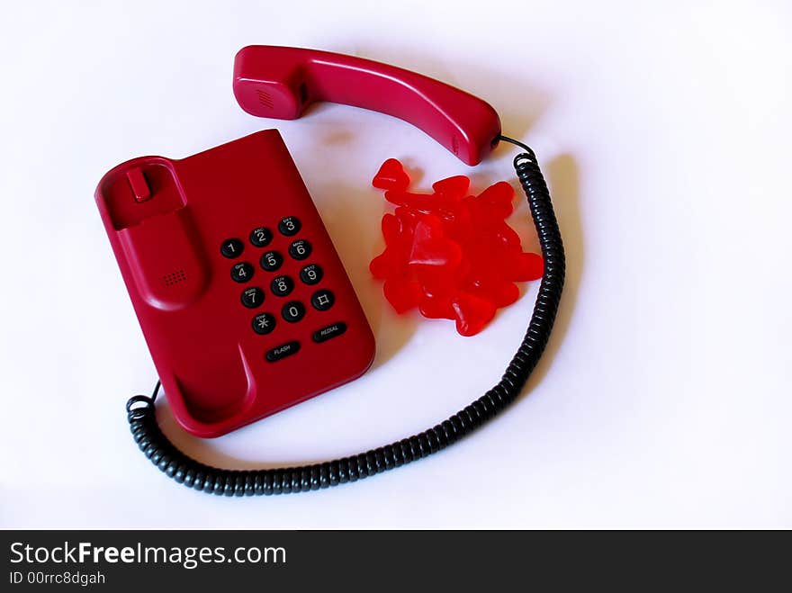 Red telephone with gummy hearts bonbons over white background. Red telephone with gummy hearts bonbons over white background