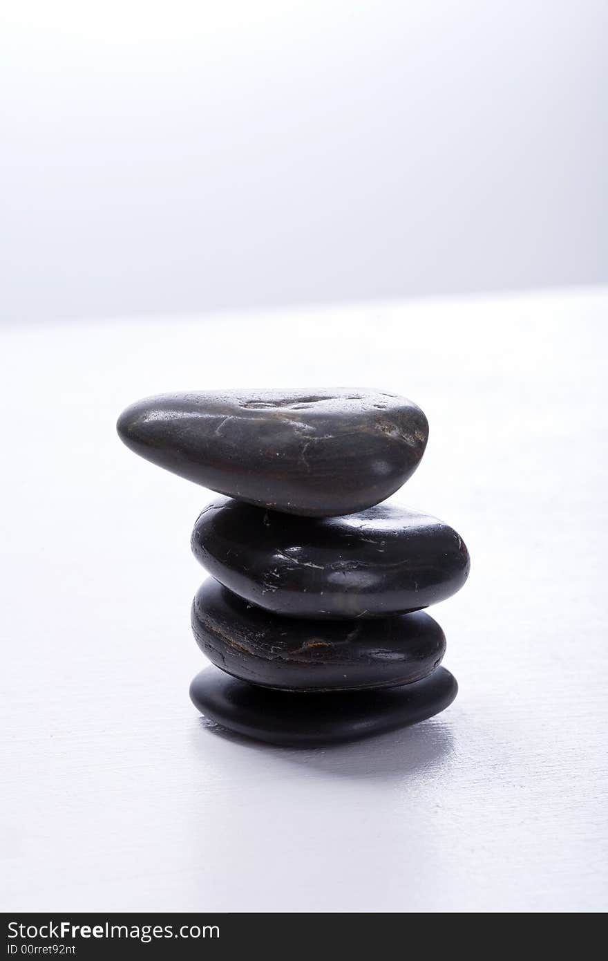 Four stapled, round, smooth black stones. Zen-Style. White background. Reassuring. Four stapled, round, smooth black stones. Zen-Style. White background. Reassuring.