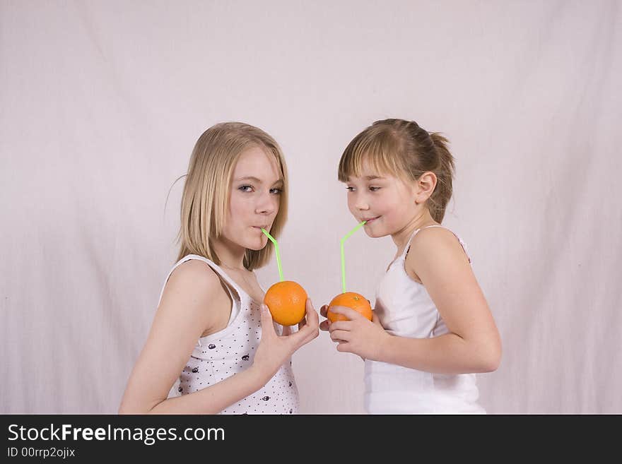 Two girls drinking juice from an orange. Two girls drinking juice from an orange