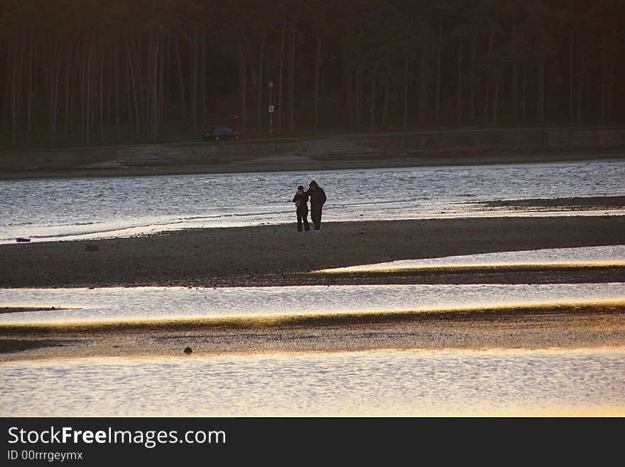 Lovers walking by the sea, during low tide; suitable for conceptual love and Valentine cards