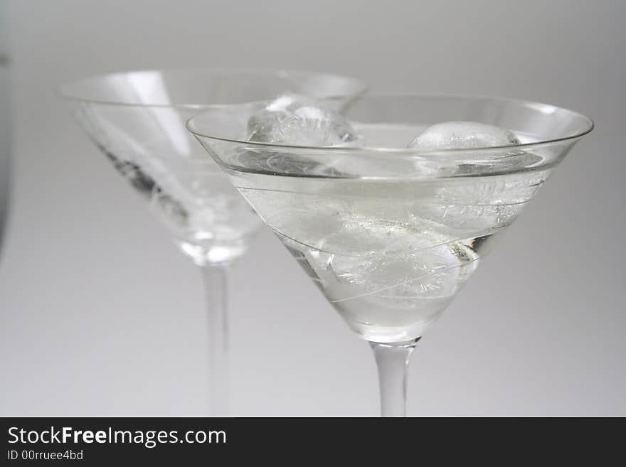 Two martini glasses, one with vermouth and ice