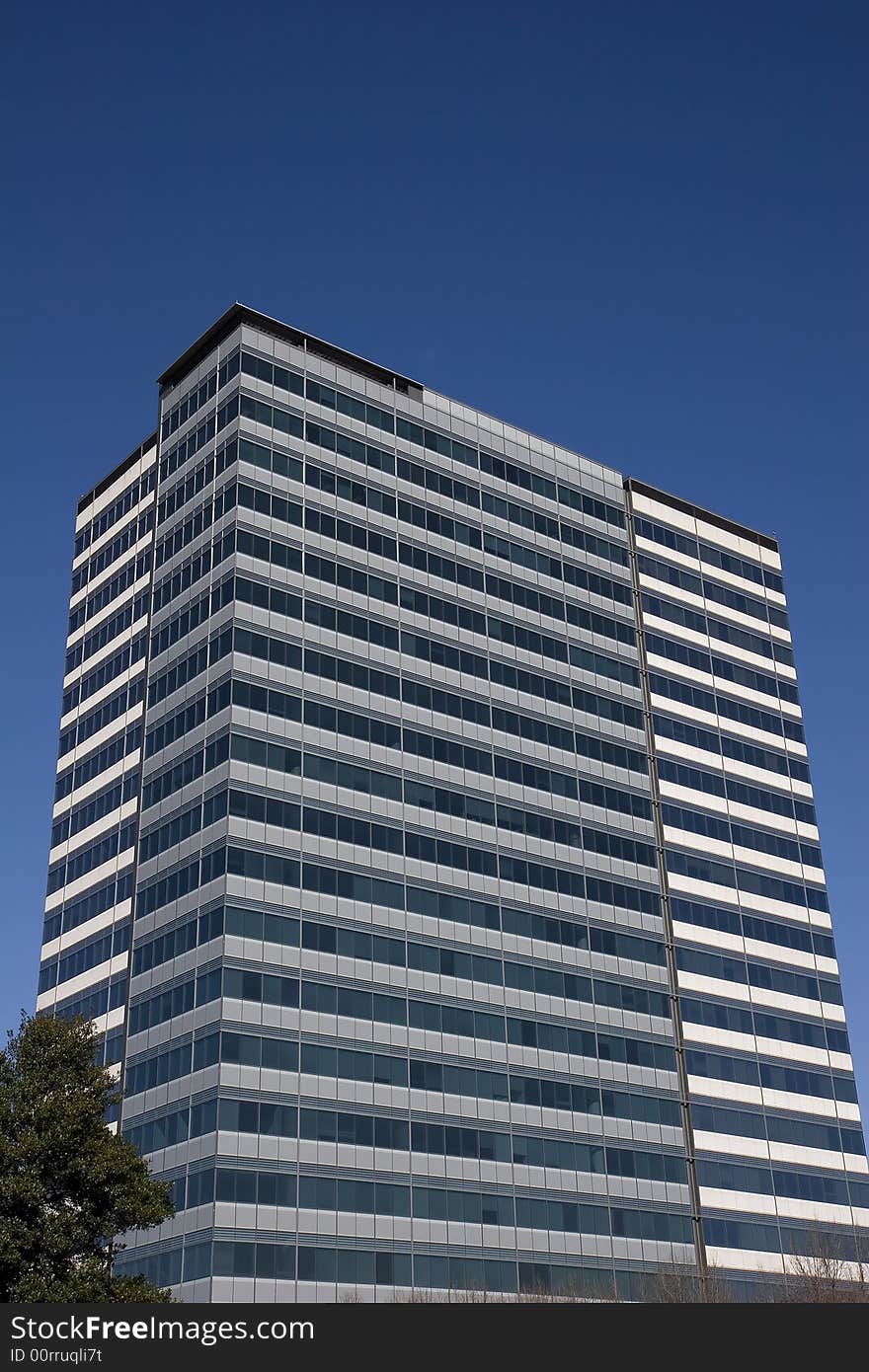 A building of grey concrete and blue glass against the sky. A building of grey concrete and blue glass against the sky