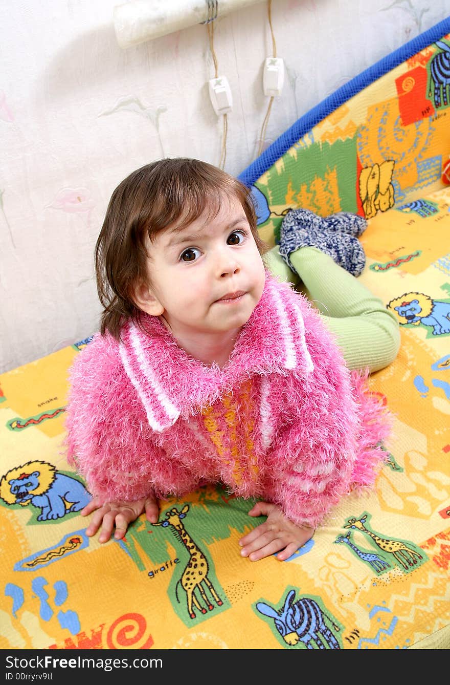 Happy baby girl lays on a sofa