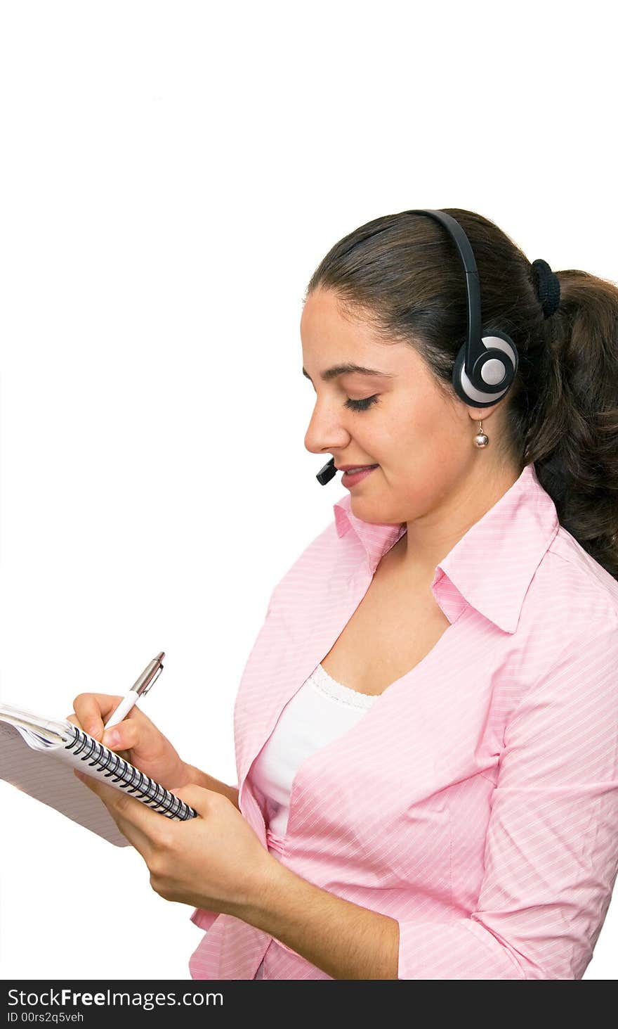 A girl, wearing headphones and microphone, writing down in her notebook. A girl, wearing headphones and microphone, writing down in her notebook