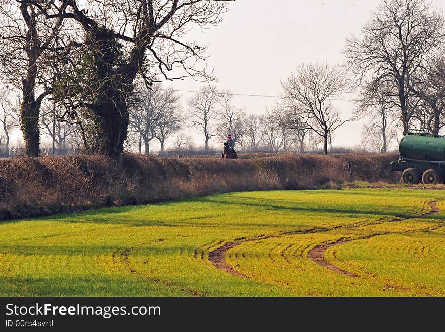 A country scene with farm machines and a horse and rider