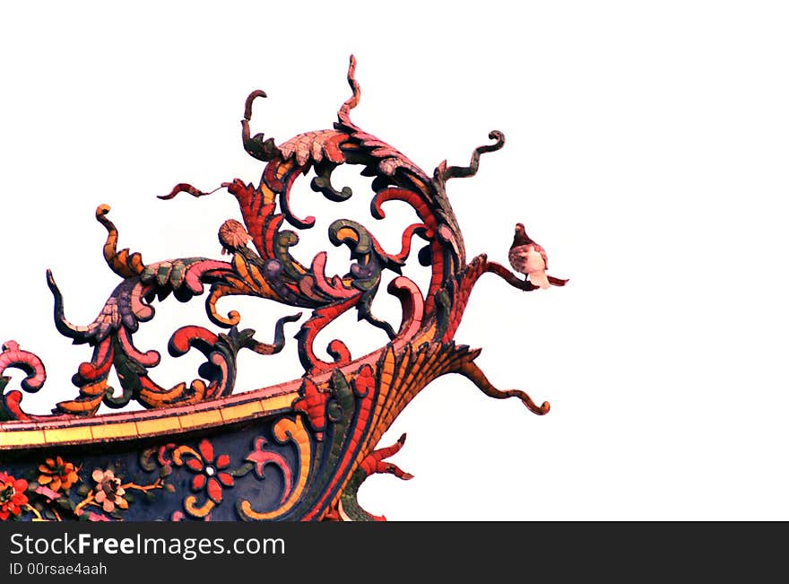 Colorful delicate phoenix tail wood carvings on a Buddhist Temple.phoenix tail shaped wood carving where a pigeon stand perching. Colorful delicate phoenix tail wood carvings on a Buddhist Temple.phoenix tail shaped wood carving where a pigeon stand perching.