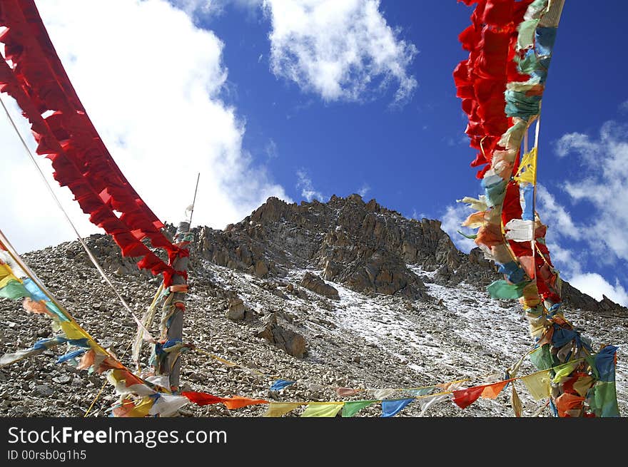 Prayer flag is waving with the blue sky and snow mountain background