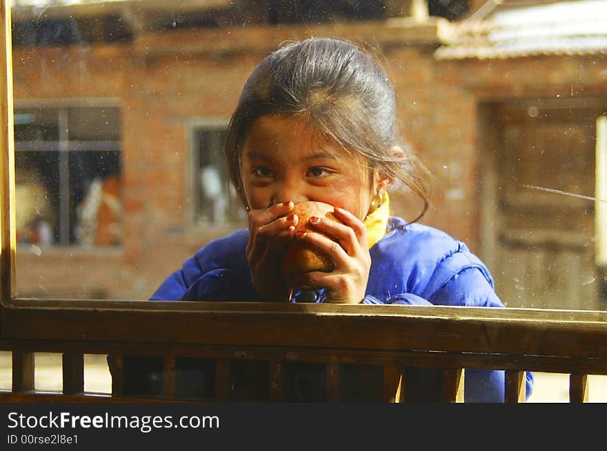 Little girl with an apple outside of window