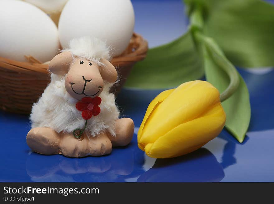 Easter motive.Easter lamb with yellow tulip,white eggs on blue background.