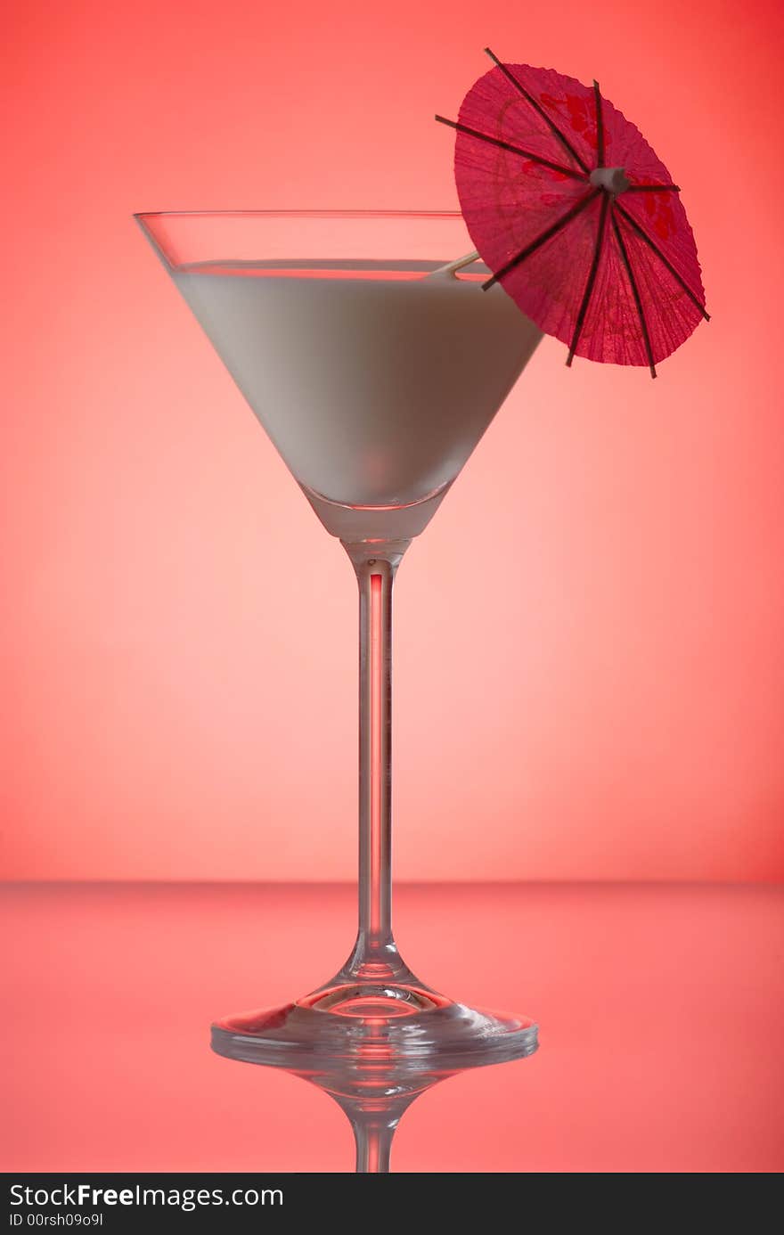 Milky cocktail with umbrella on red background