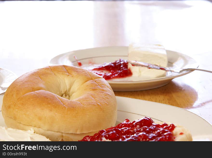 Breakfast of plain bagel with cream cheese and strawberry preserves. Breakfast of plain bagel with cream cheese and strawberry preserves.