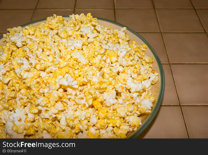 A freshly buttered bowl of popcorn for use as a background or party announcement. A freshly buttered bowl of popcorn for use as a background or party announcement