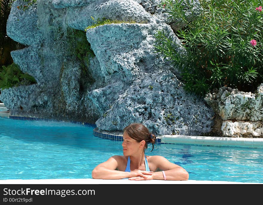 The girl is resting on a side of a pool on Grand Cayman island. The girl is resting on a side of a pool on Grand Cayman island.