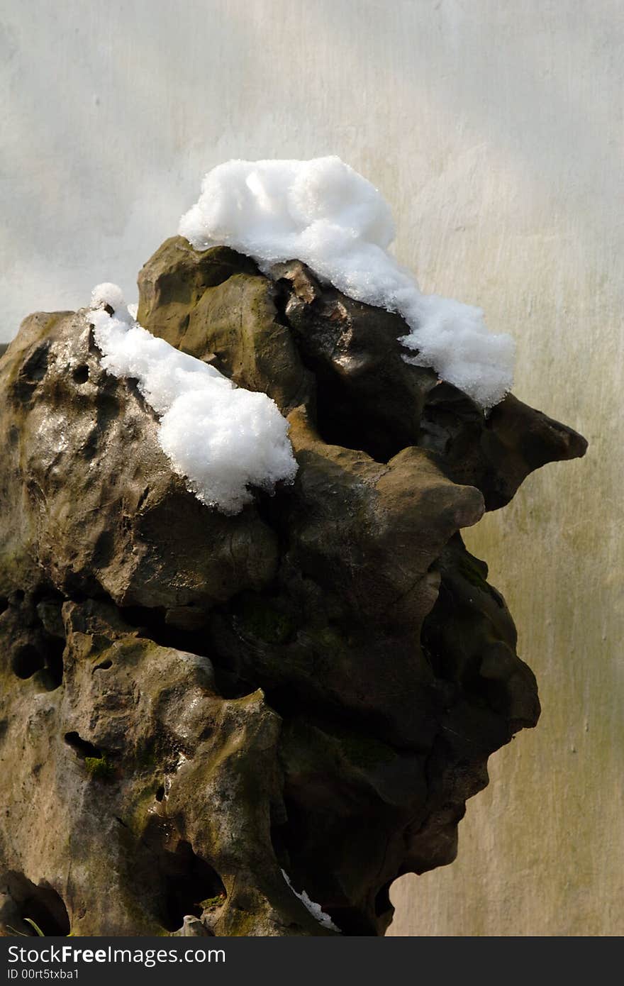 A huge ugly stone with its top covered with snow.  
This picture is taken in Zhuozheng park in Suzhou ,China