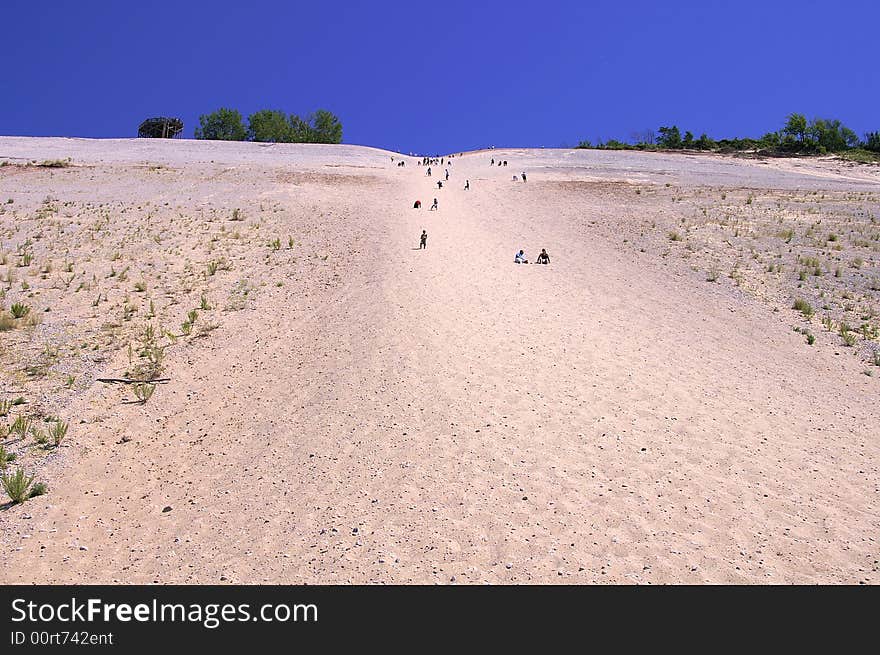 Many people climbing a steep dune. Many people climbing a steep dune