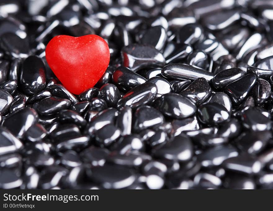 Red candy heart on shiny pebbles. Red candy heart on shiny pebbles