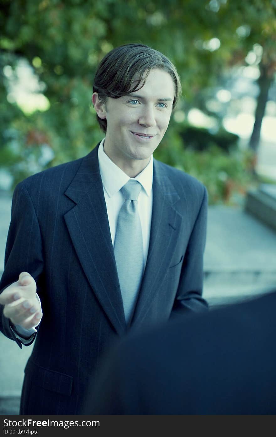 Over shoulder view of businessman standing in suit and tie talking. Over shoulder view of businessman standing in suit and tie talking