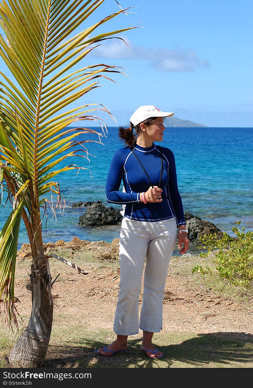 The girl is standing by the little palm on St.Thomas island, U.S. Virgin Islands. The girl is standing by the little palm on St.Thomas island, U.S. Virgin Islands.