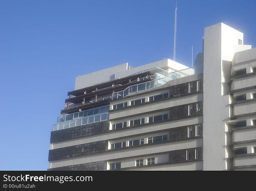 A white luxury resort hotel against a blue sky. A white luxury resort hotel against a blue sky