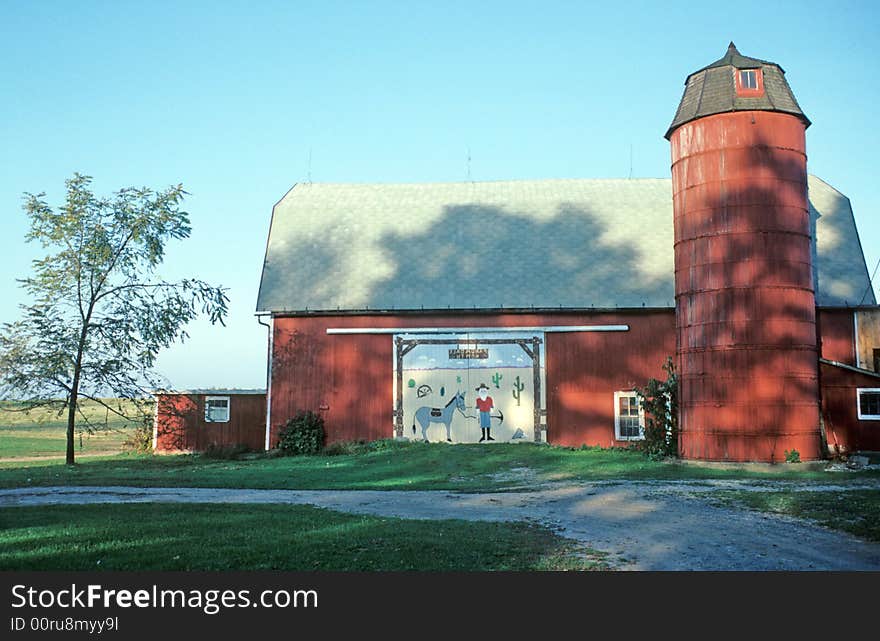 An old barn and silo has a new mural on the entrance way. An old barn and silo has a new mural on the entrance way