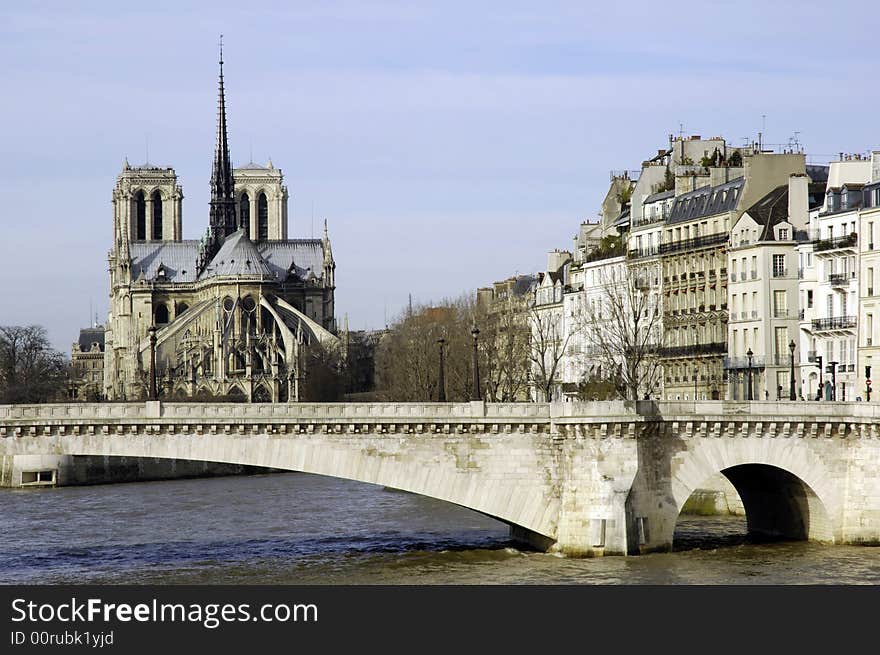 France, Paris: nice city view from the quai of the seine river; blue sky; naked trees and the river tranquility for this winter view of Paris with Notre Dame cathedral at the background and a nice ancient bridge. France, Paris: nice city view from the quai of the seine river; blue sky; naked trees and the river tranquility for this winter view of Paris with Notre Dame cathedral at the background and a nice ancient bridge