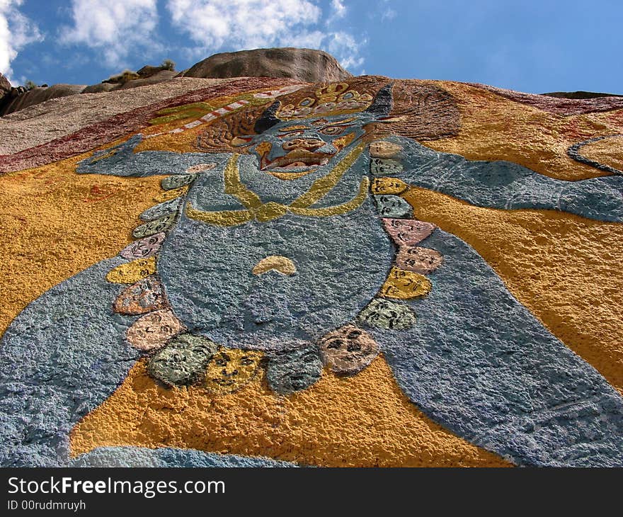 This is a tibetan buddhism joss carved in a huge rock more than six metres high. A trail of death's-heads is hung on its body. From this you can see what a terrible religion the Tibetan Buddhism is.