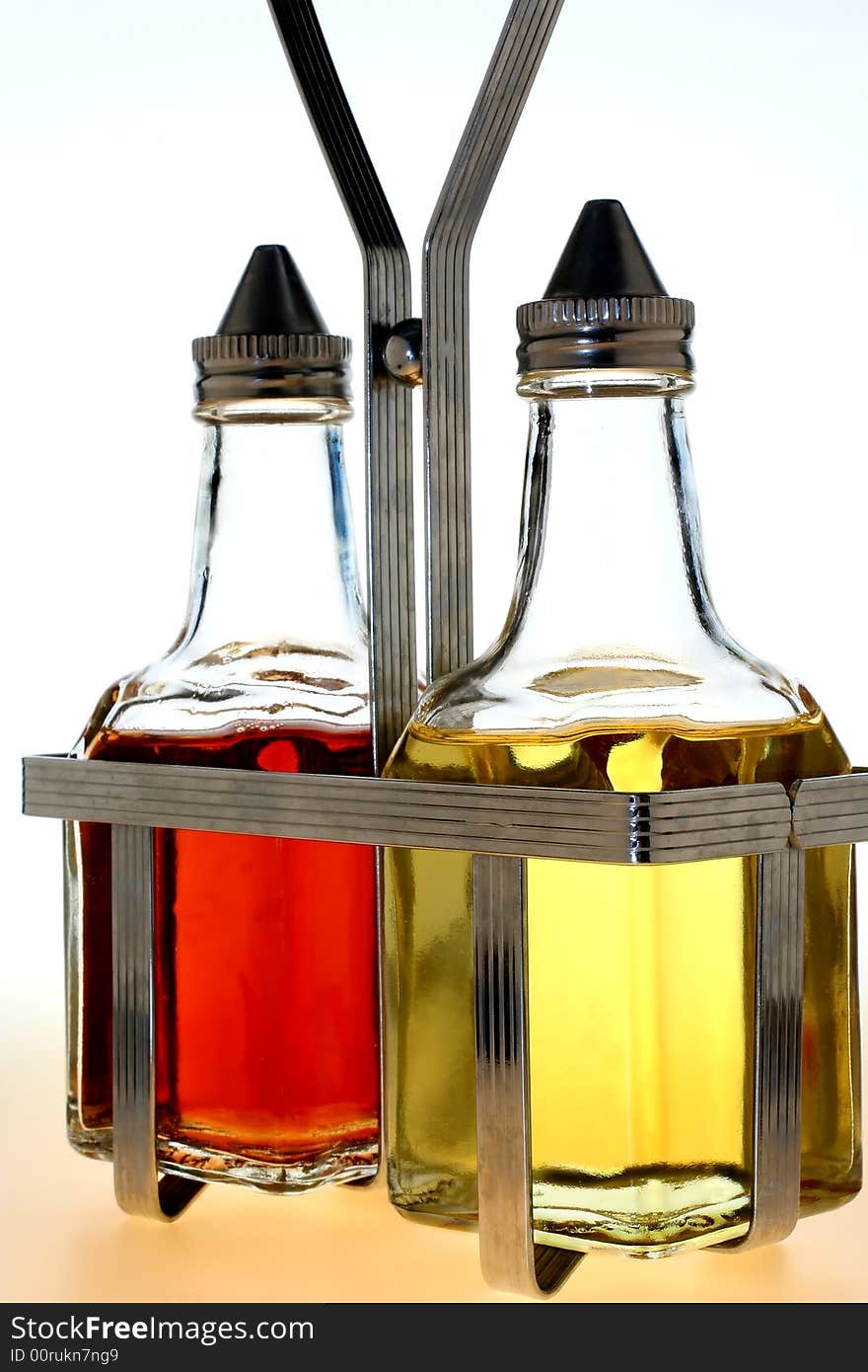 Oil and vinegar bottles in a wire rack on white background. Oil and vinegar bottles in a wire rack on white background.