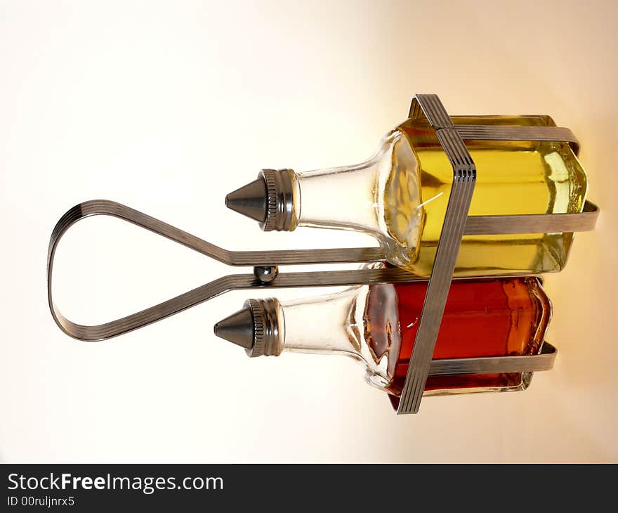 Oil and vinegar bottles in a wire rack on white background. Oil and vinegar bottles in a wire rack on white background.