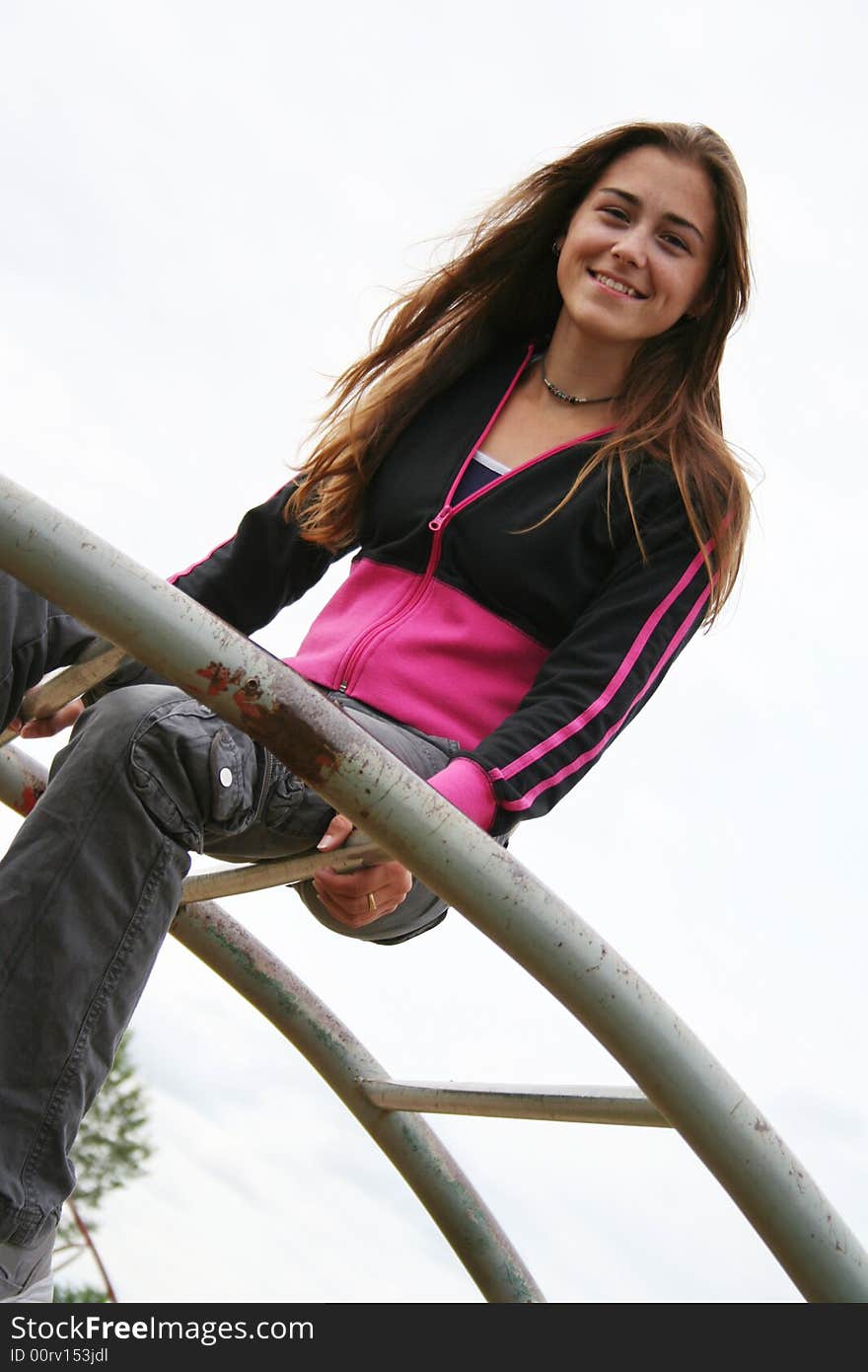 Pretty girl sitting on monkey bars. Pretty girl sitting on monkey bars.