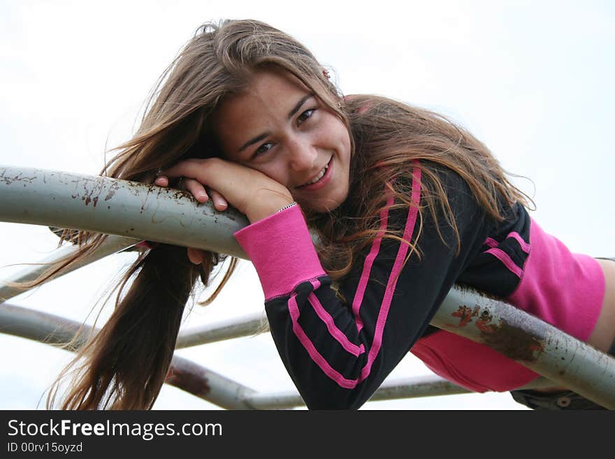 Pretty girl laying on the top of monkey bars. Pretty girl laying on the top of monkey bars.