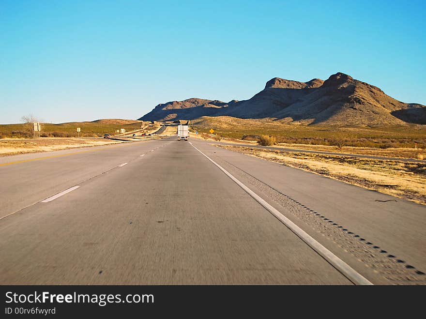 Driving on Interstate 10 as the sun sets to the west casting a shadow on the arid desert mountains in West Texas. Driving on Interstate 10 as the sun sets to the west casting a shadow on the arid desert mountains in West Texas.