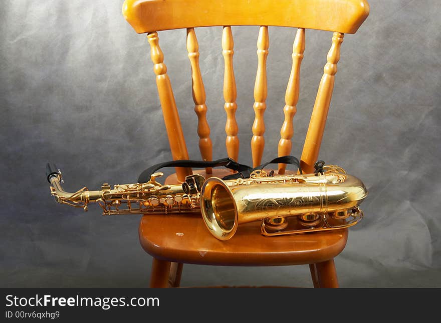 The saxophone lays on a chair. The saxophone lays on a chair