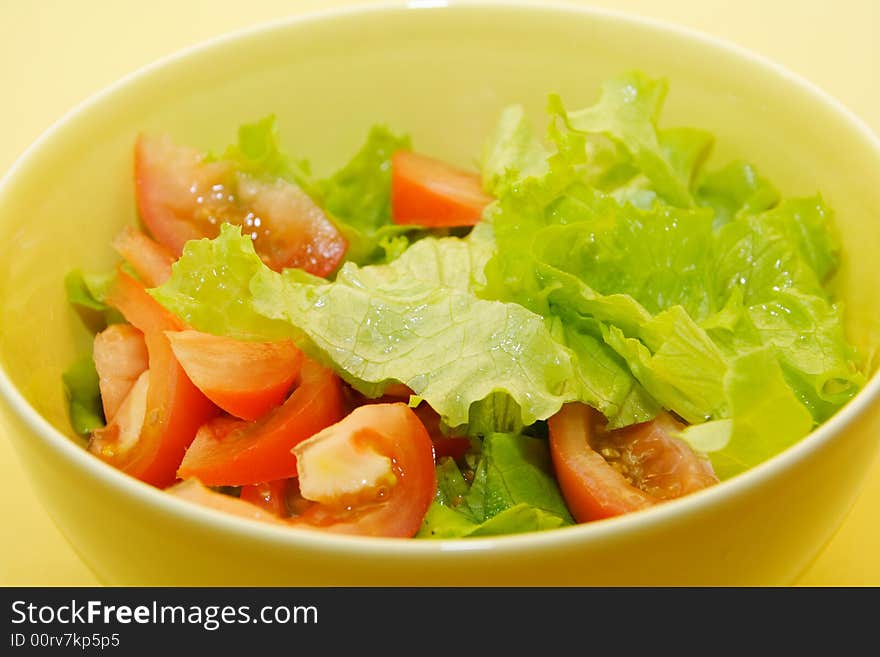 Bowl of fresh salad on yellow background