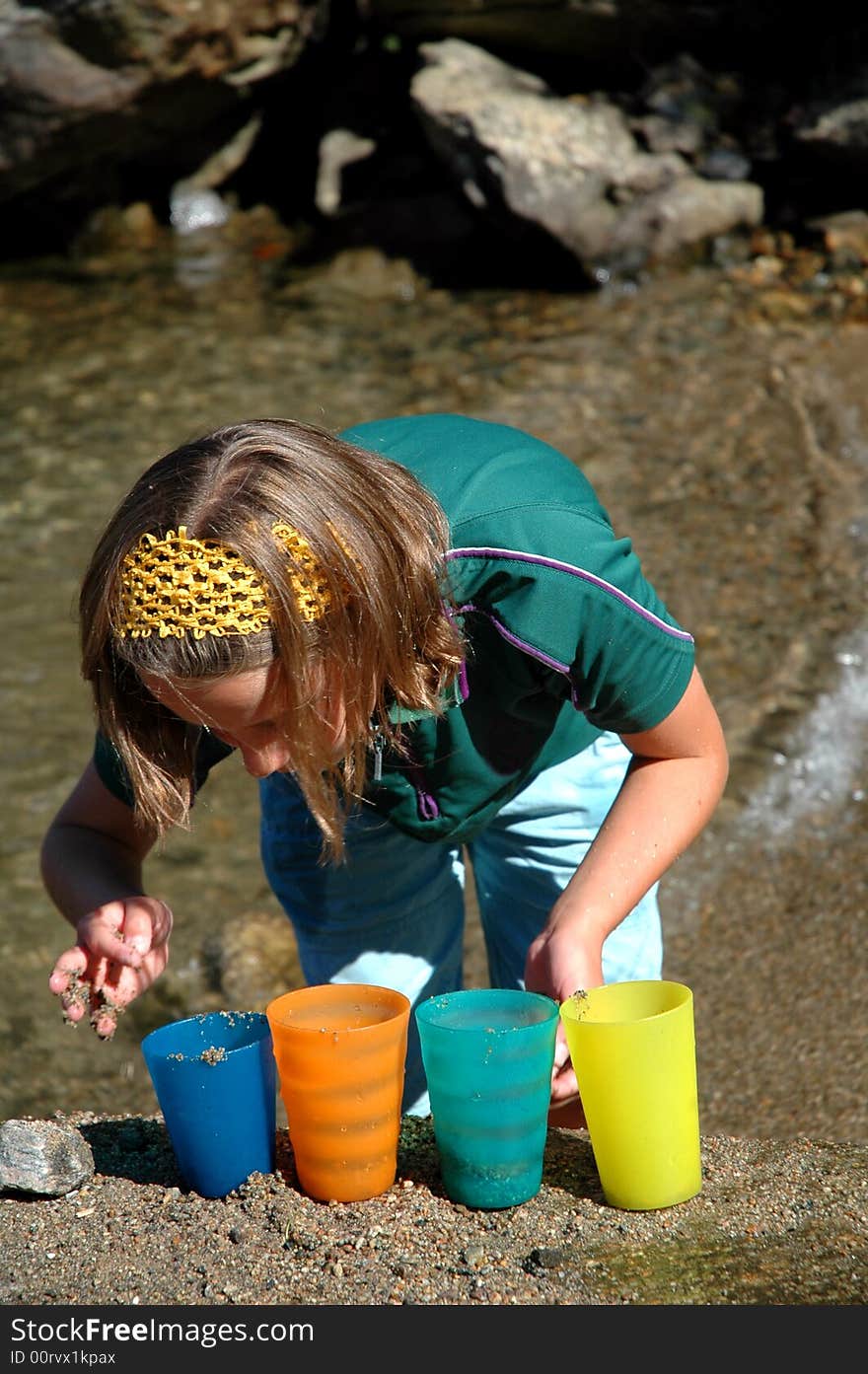 Girl playing with colourful cups in the sand