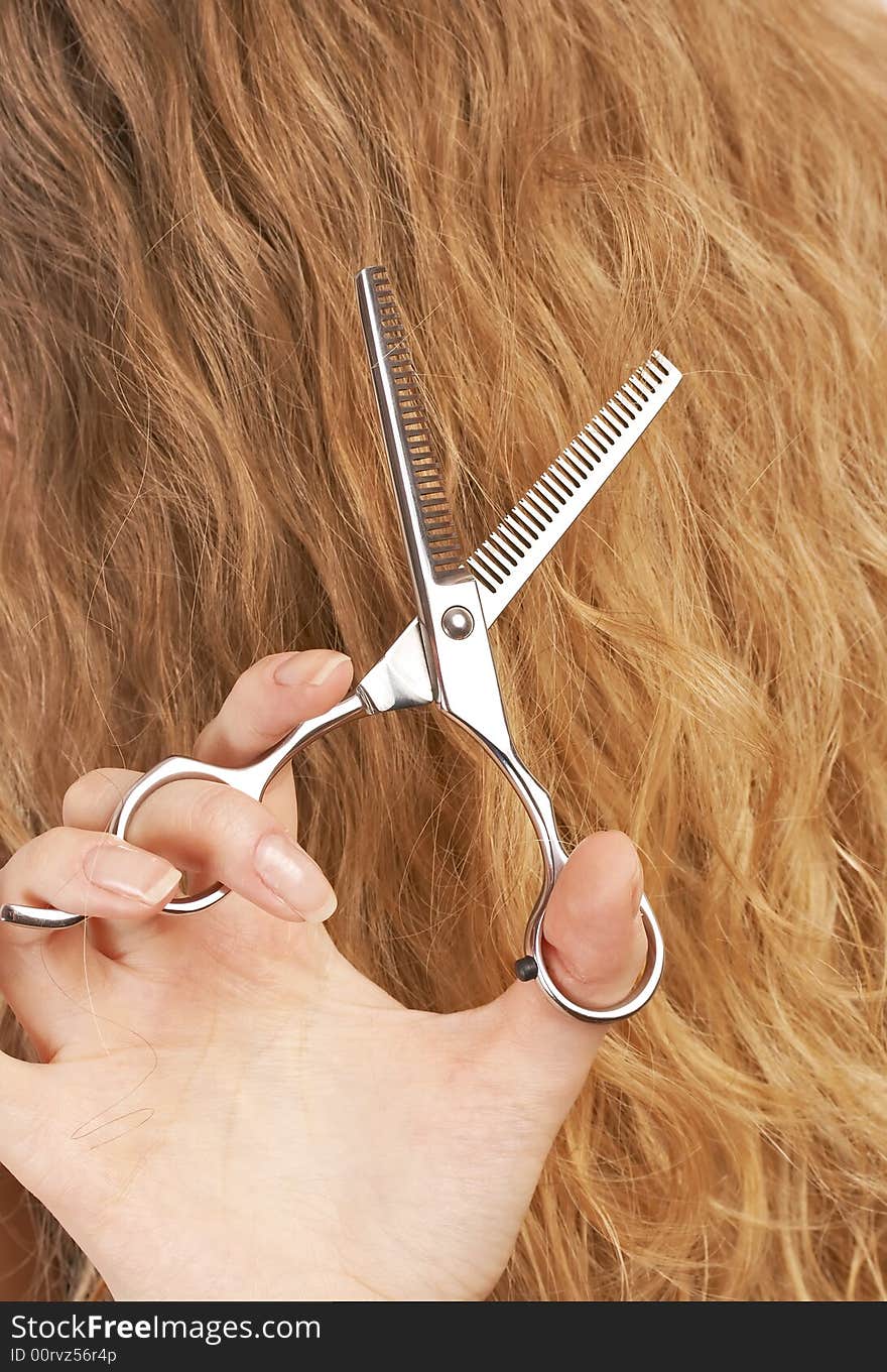 Hairstylist cutting long blond hair with professional scissors