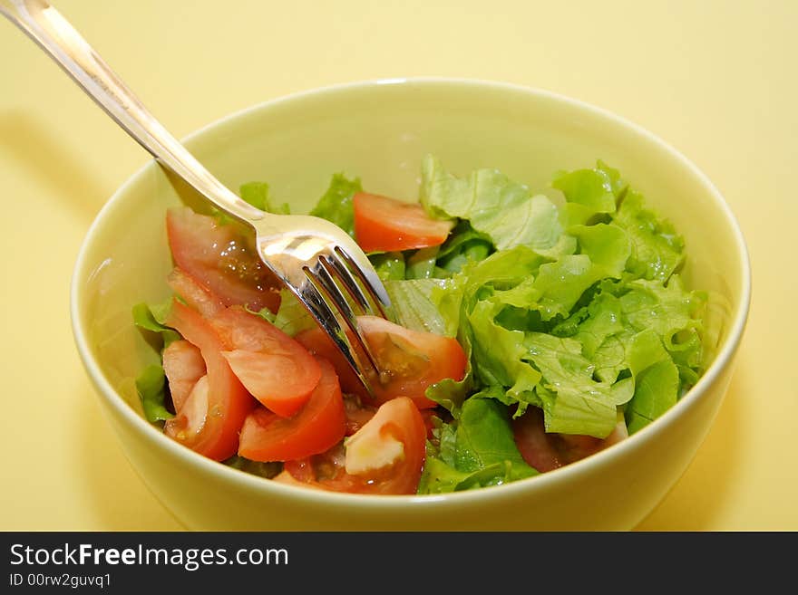 Bowl of fresh salad on yellow background