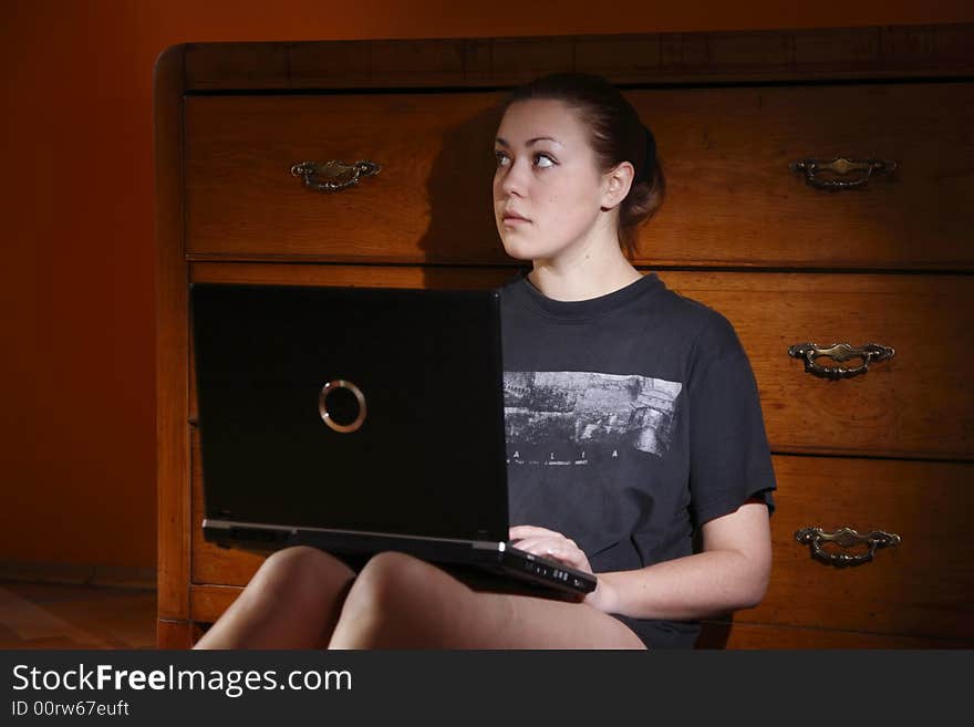 A girl with a laptop in the dark retro-styled apartment. A girl with a laptop in the dark retro-styled apartment.