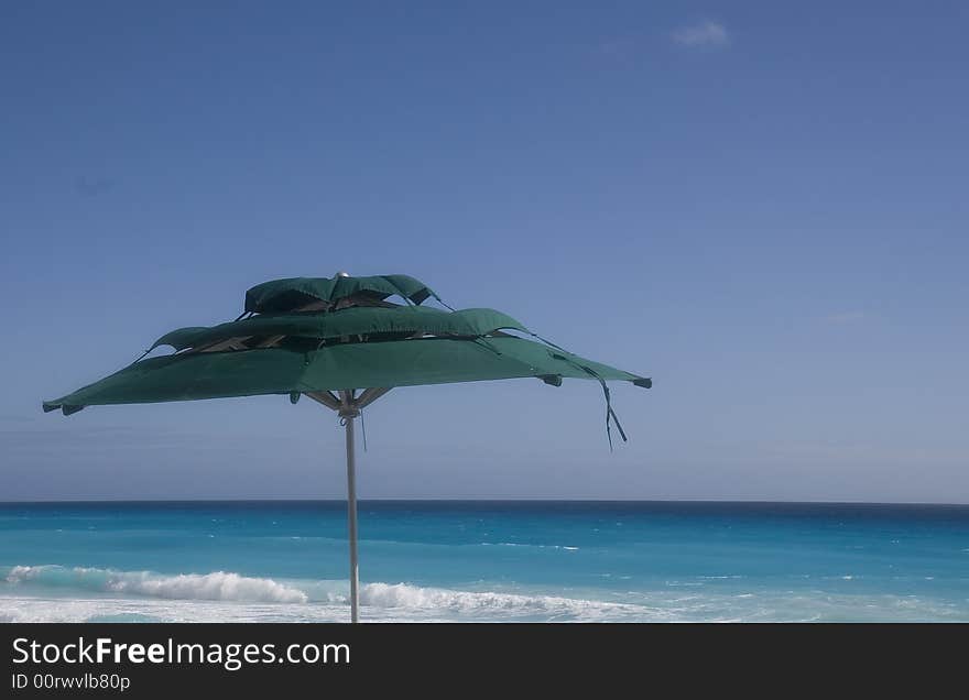 A green sun umbrella against a blue sky and ocean. A green sun umbrella against a blue sky and ocean