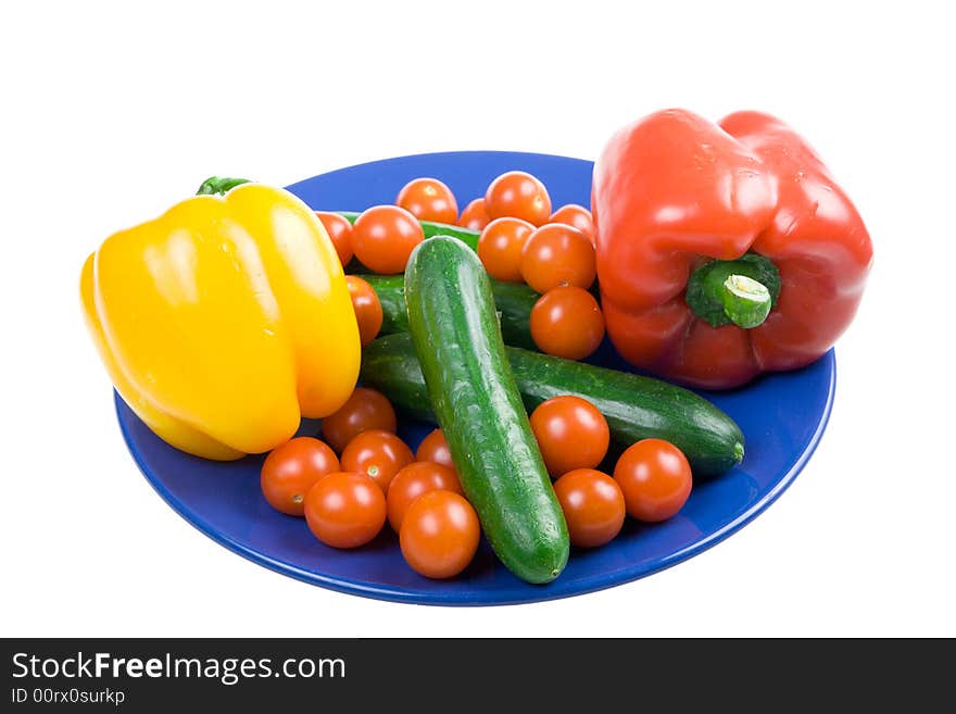 Set of vegetables on a dark blue plate isolated on a white background. Set of vegetables on a dark blue plate isolated on a white background