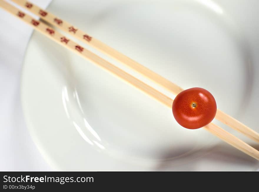 Cherry tomatoe on a white plate with chopsticks. Cherry tomatoe on a white plate with chopsticks