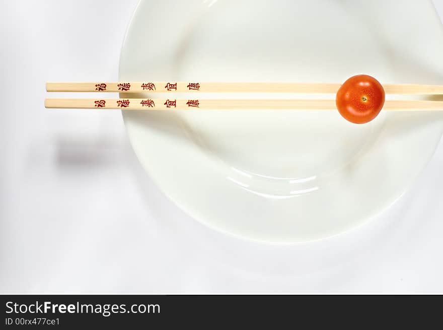 Cherry tomatoe on a white plate with chopsticks. Cherry tomatoe on a white plate with chopsticks