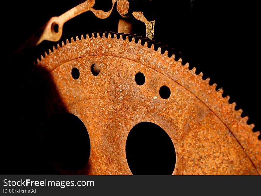 Soft focus image of rusty gears in junk yard against black backdrop with circles and various shapes and forms