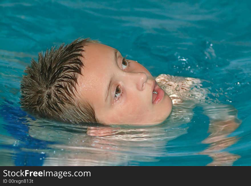 A young boy swimming in a pool. A young boy swimming in a pool