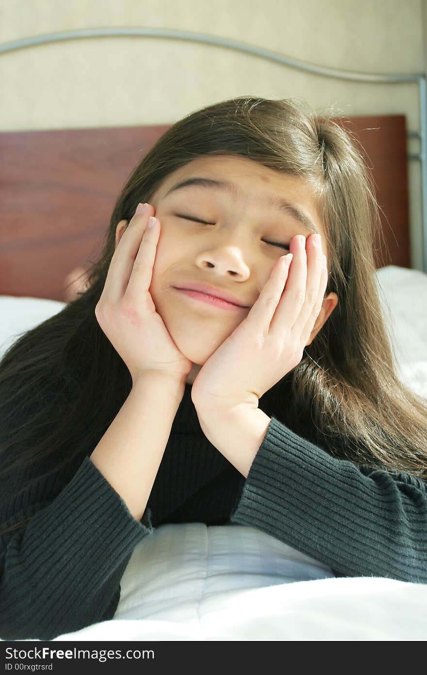 Six year old girl chin on hands enjoying peace and quiet while lying down on bed. Six year old girl chin on hands enjoying peace and quiet while lying down on bed