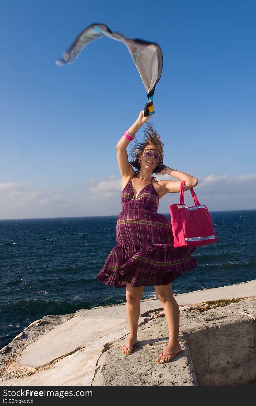 Happy casual girl waving a scarf in ocean background. Happy casual girl waving a scarf in ocean background