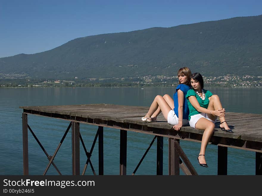 Young woman sitting on a pontoon at the edge of a lake. Young woman sitting on a pontoon at the edge of a lake