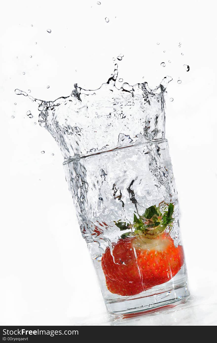 A strawberry making its way into a glass full of water. A strawberry making its way into a glass full of water