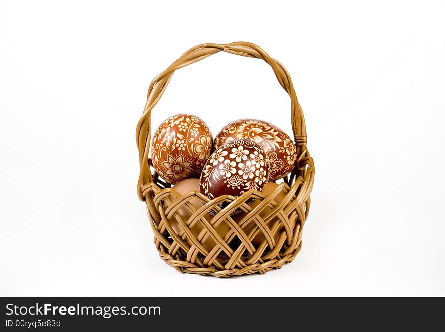 Wicker basket full of easter eggs on white background