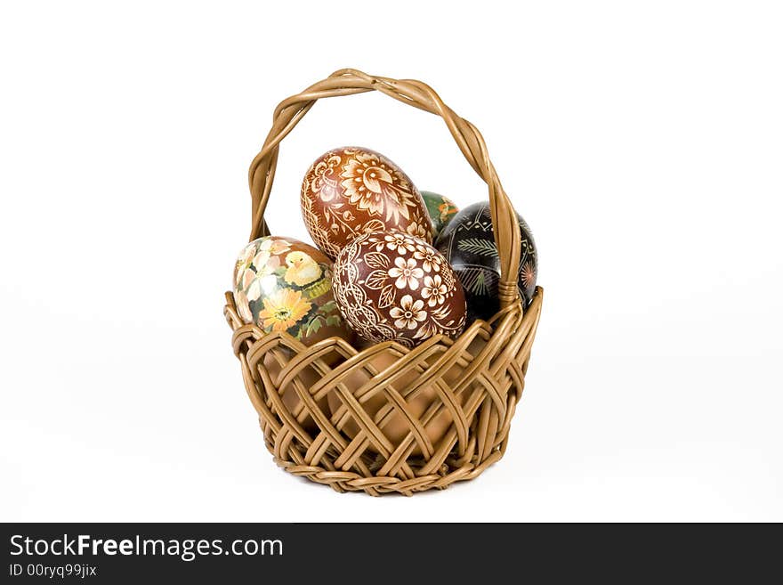 Wicker basket full of easter eggs on white background